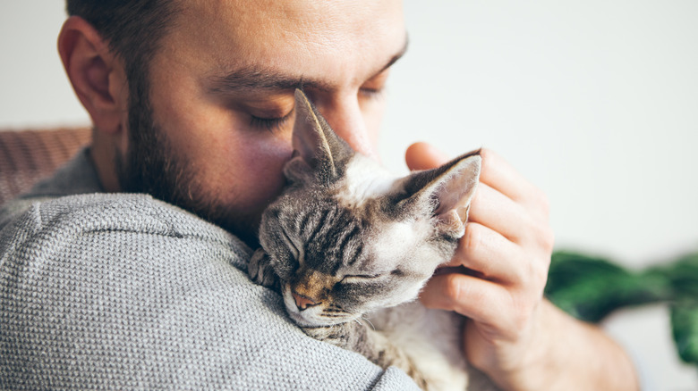 A man cuddling with a cat 