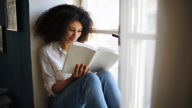 woman sitting in a window reading