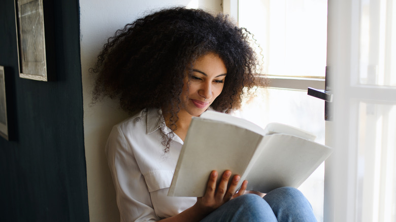 women reading book in window seat