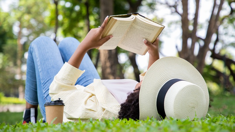 woman laying in grass reading