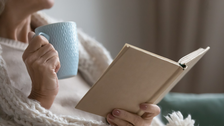 woman holding book and mug