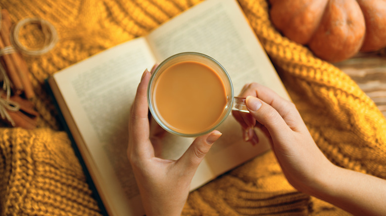 Woman holding mug of coffee while reading