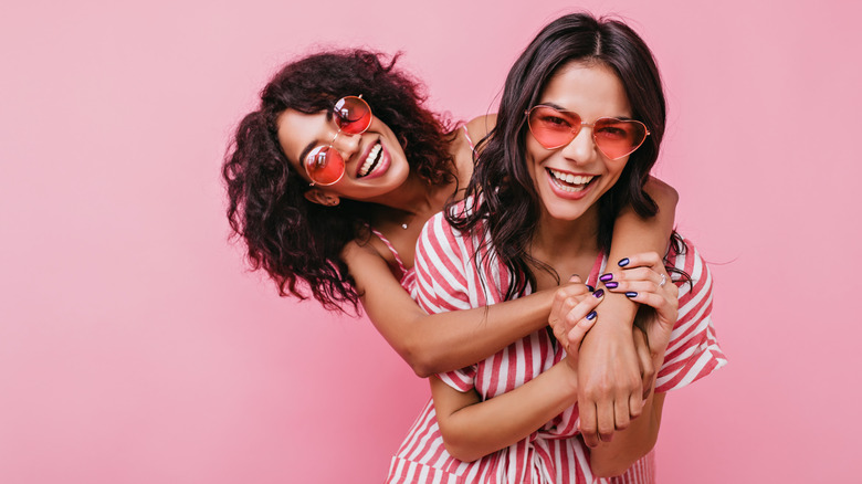 Two friends with pink sunglasses laughing and posing