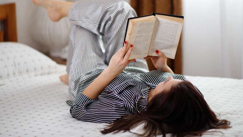 woman laying in bed reading a book