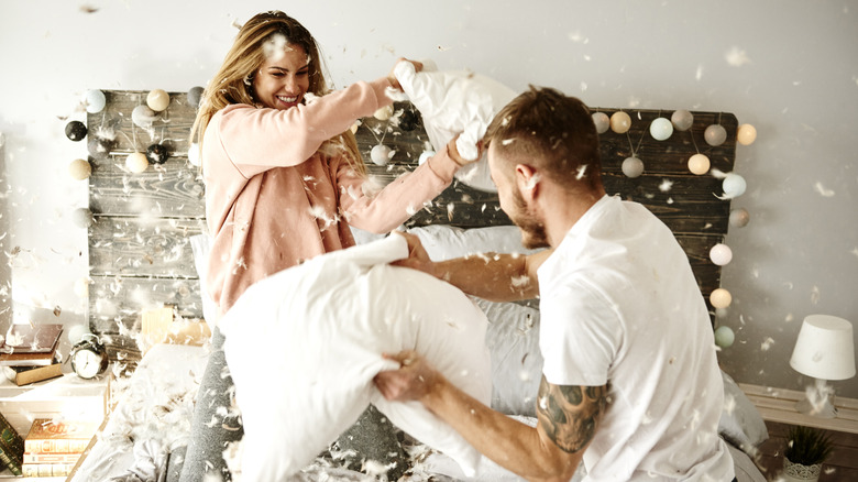 Couple having a pillow fight in bed 