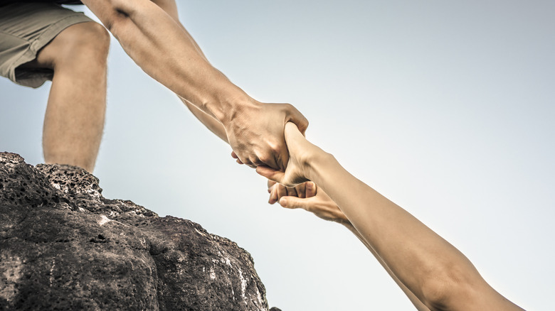 Hand reaching out to help someone up a mountain