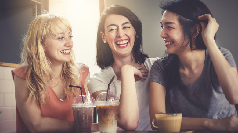 Three women laughing with iced coffee