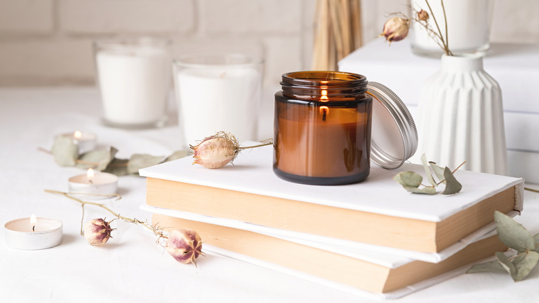 candle with dried flowers on a book on a white surface