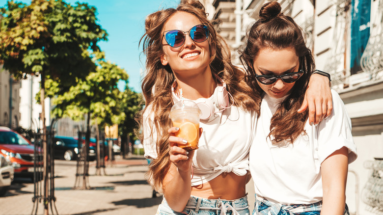 Two friends taking a stroll outside drinking juice