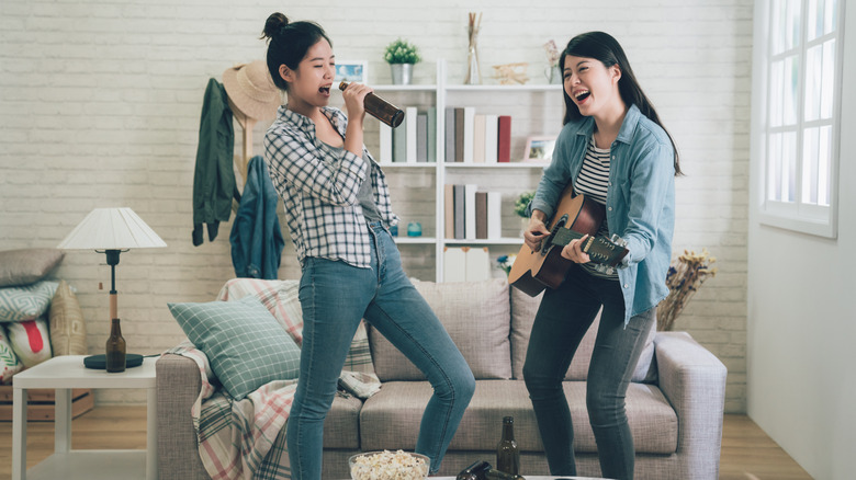 Two friends playing guitar and singing at home