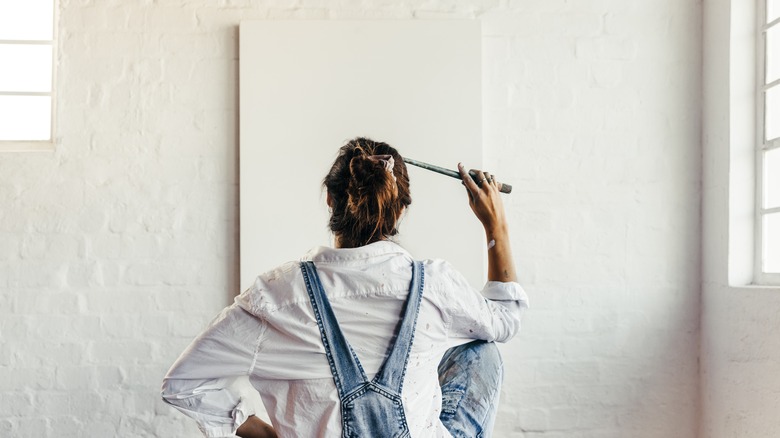 Woman contemplating blank canvas