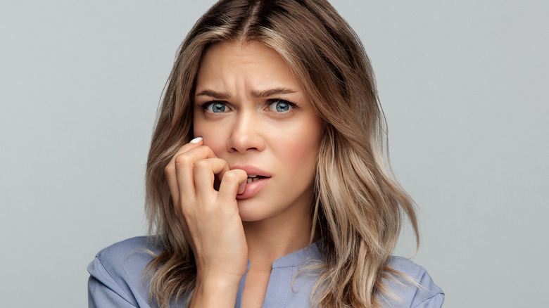 A young woman bites her nails 