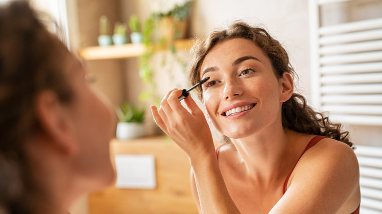 woman putting on mascara