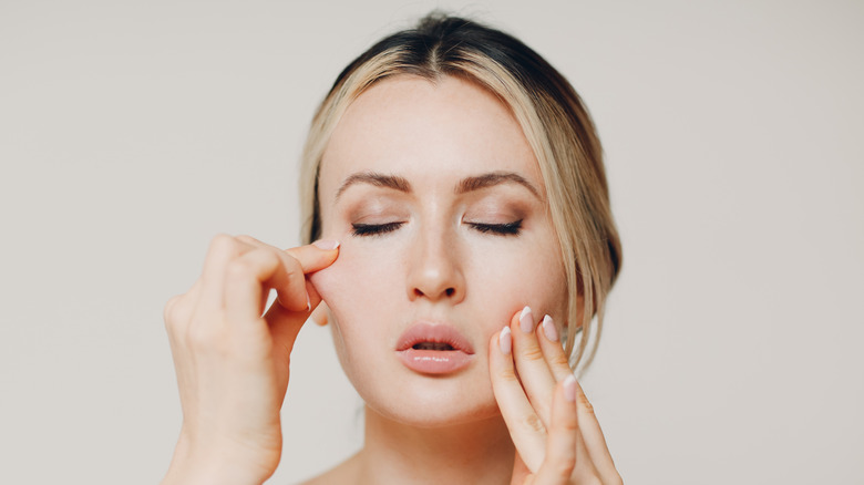 woman giving herself a facial massage