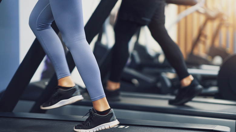 Friends run on treadmills at the gym