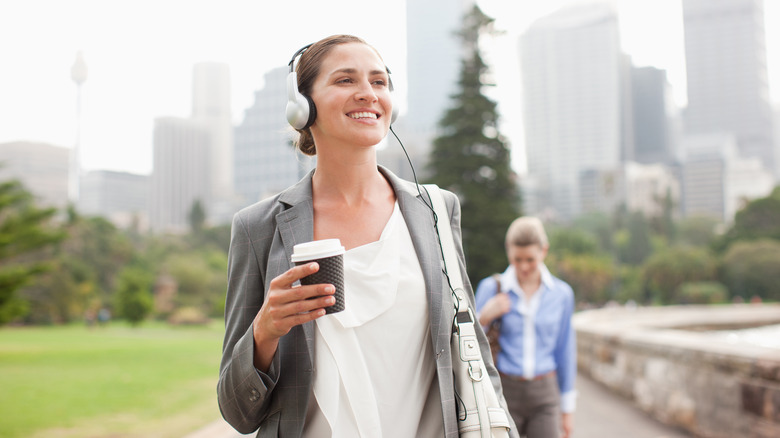 Woman with coffee and headphones walking