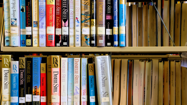 A book shelf with Danielle Steel books on them. 