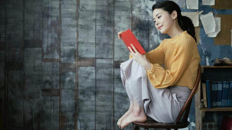 young woman sitting in chair reading