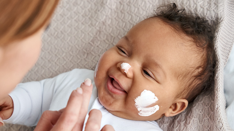 Giggling Black baby with lotion