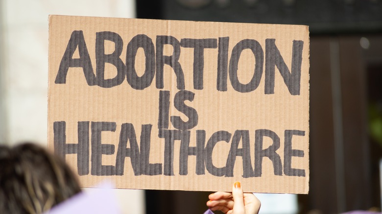 hand holding a sign at a pro-abortion rally saying "Abortion is Healthcare"