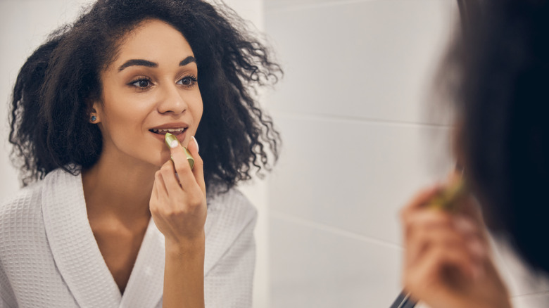 Woman applying lip balm in mirror