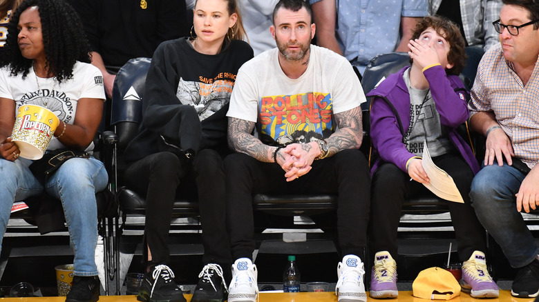 Behati Prinsloo and Adam Levine sitting courtside