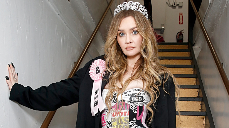 Anna Delvey with tiara, pink prize ribbon, black jacket