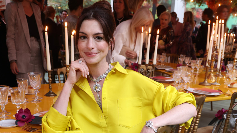 Anne Hathaway sitting at a table