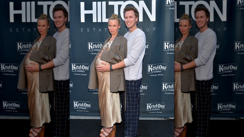 Barron Hilton holding Tessa Hilton's baby bump at event