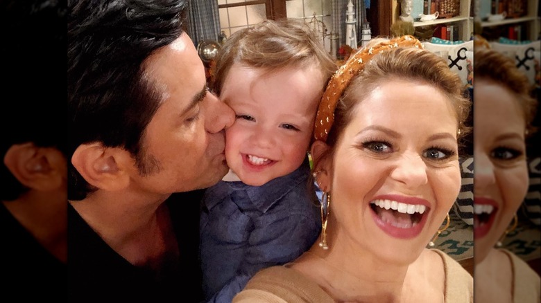 Candace Cameron Bure smiling while John Stamos kisses Billy Stamos on the cheek