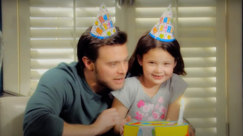 Billy and Delia wearing party hats in front of a birthday cake