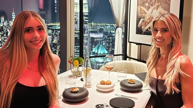 Christina Hall and her daughter sit at dinner smiling with views of NYC skyline