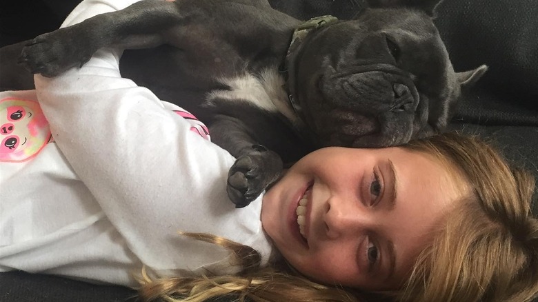 Christina Hall's daughter Taylor lies on a couch cuddling her black puppy