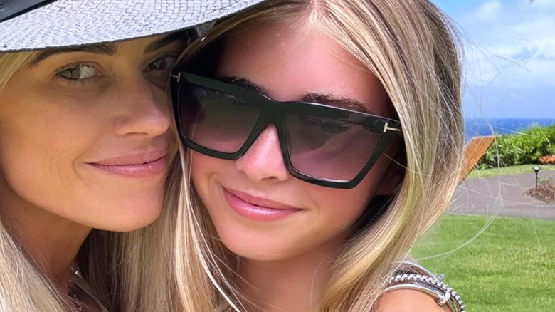 Christina Hall wears a sun hat outside smiling next to her daughter in sunglasses selfie