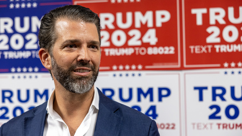 Donald Trump Jr. standing in front of campaign signs