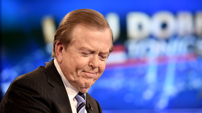 Lou Dobbs smiling, eyes downcast