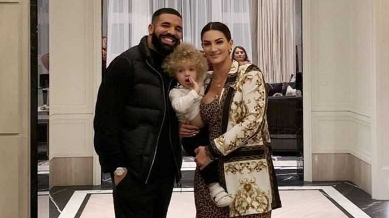 Drake and Sophie Brussaux stand and smile with son Adonis