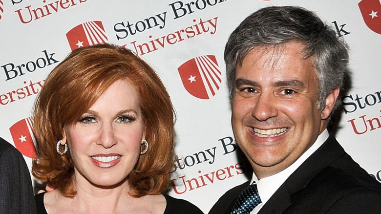 Liz Claman and Jeff Kepnes smile in fron of Stony Brook University banner