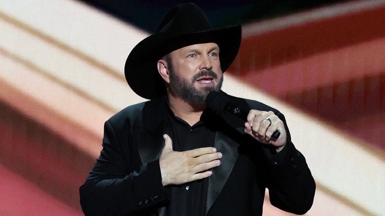 Garth Brooks speaks on stage in a cowboy hat