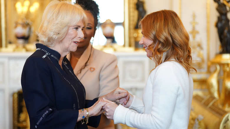 Geri Horner holding hands with Queen Camilla