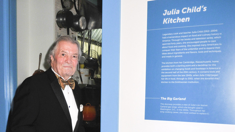 Jacques P﻿épin poses in front of Julia Child's kitchen in the Smithsonian Institute.