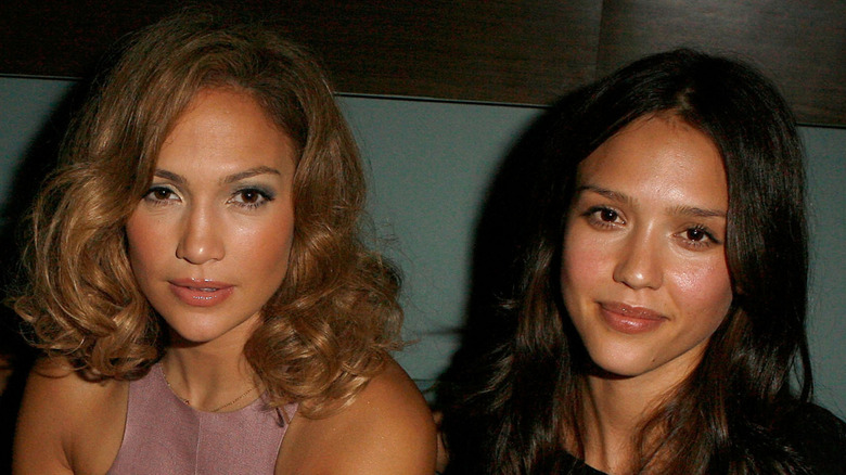 Jennifer Lopez smirking next to Jessica Alba.