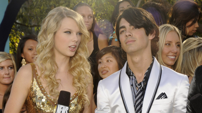 Taylor Swift holding microphone standing next to Joe Jonas