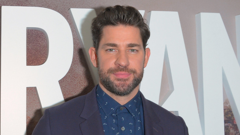 John Krasinski posing for a photo in a dark blue patterned button-up and suit jacket