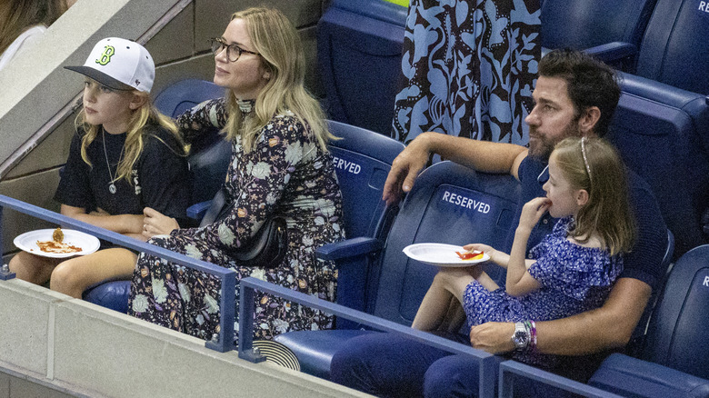 John Krasinski, Emily Blunt, and daughters Hazel and Violet sitting in stadium seats