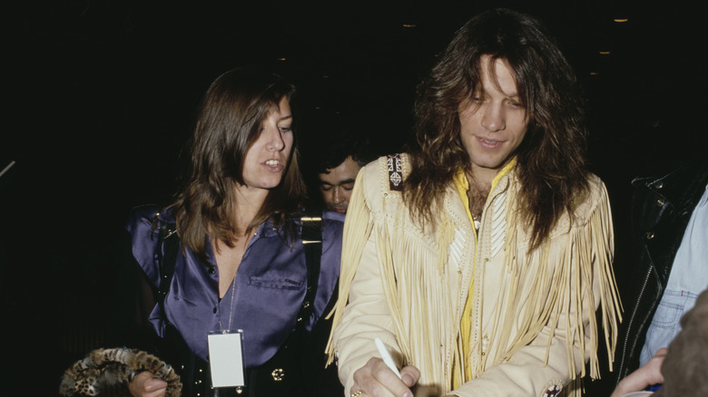 Jon Bon Jovi signing autographs in fringed jacket with Dorothea Hurley in purple blouse