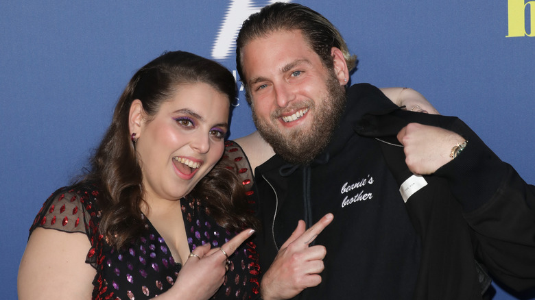 Beanie Feldstein and Jonah Hill smiling pointing at jacket