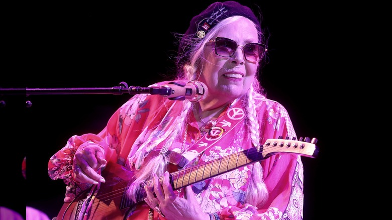 Older Joni Mitchell, braids, guitar on stage