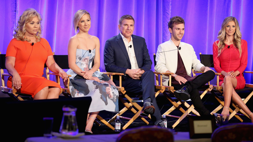 The Chrisley family sits in folding chairs on stage