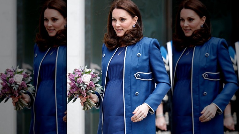 Pregnant Princess Catherine in blue coat holding flowers
